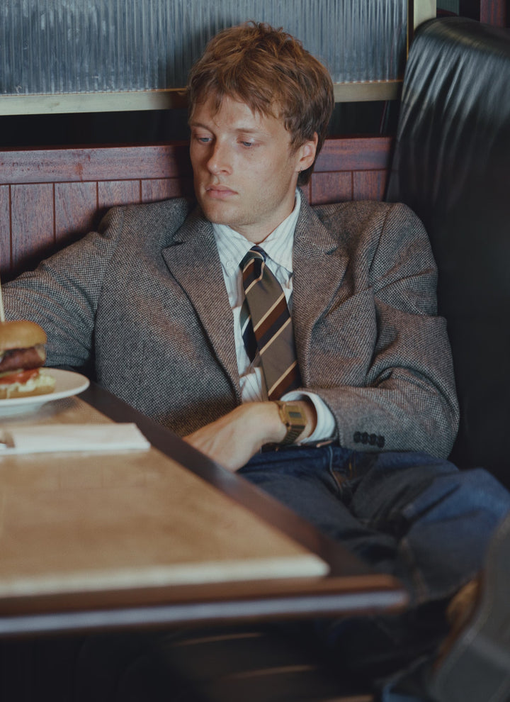A model wears the Percival silk stripe tie in forest multi, styled with a grey blazer and a striped shirt.