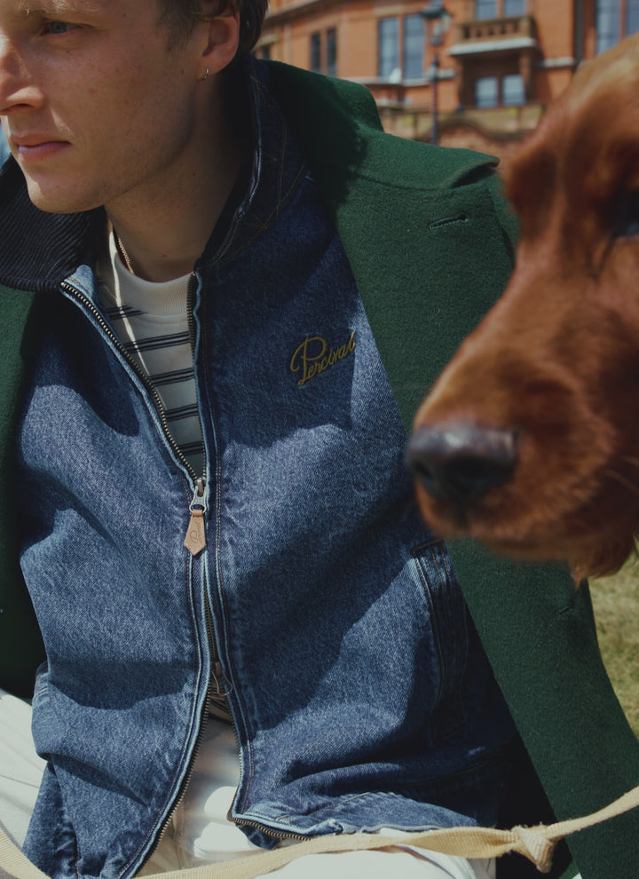 A model wearing the mid wash blue Percival Mackey denim zip jacket with a dog beside him.