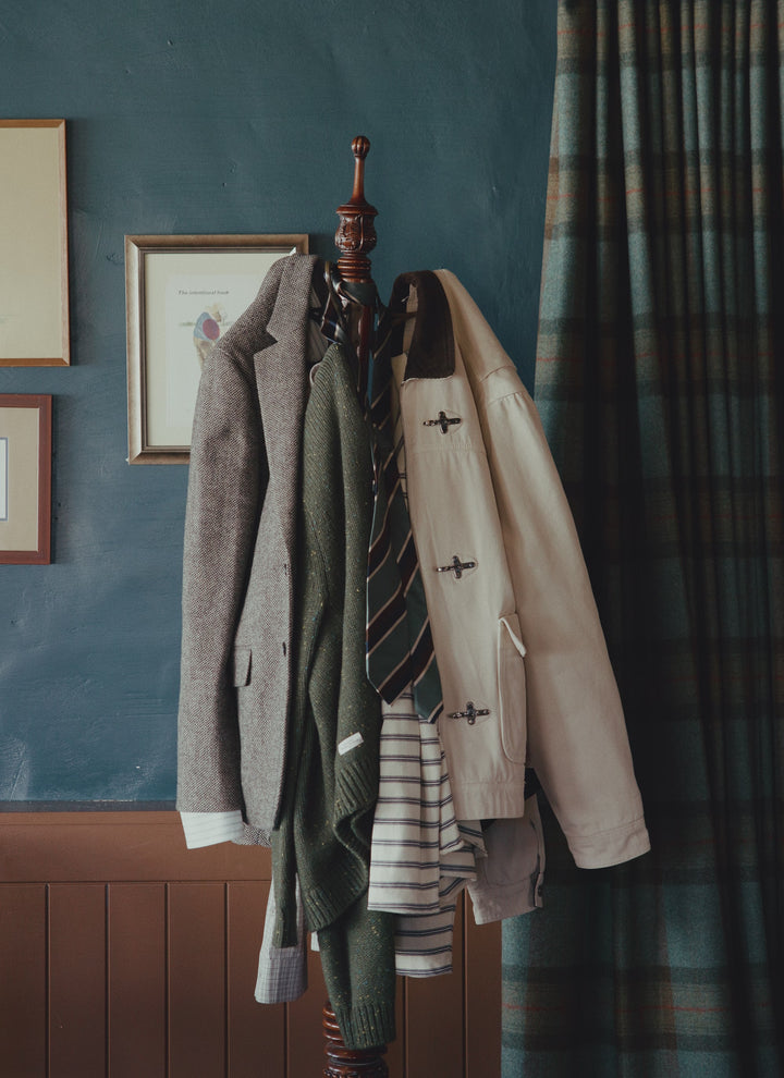 A coat stand holding a Percival cream check shirt alongside jackets and a cap.