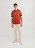 red football shirt with diamond shapes styled with ecru trousers and converse